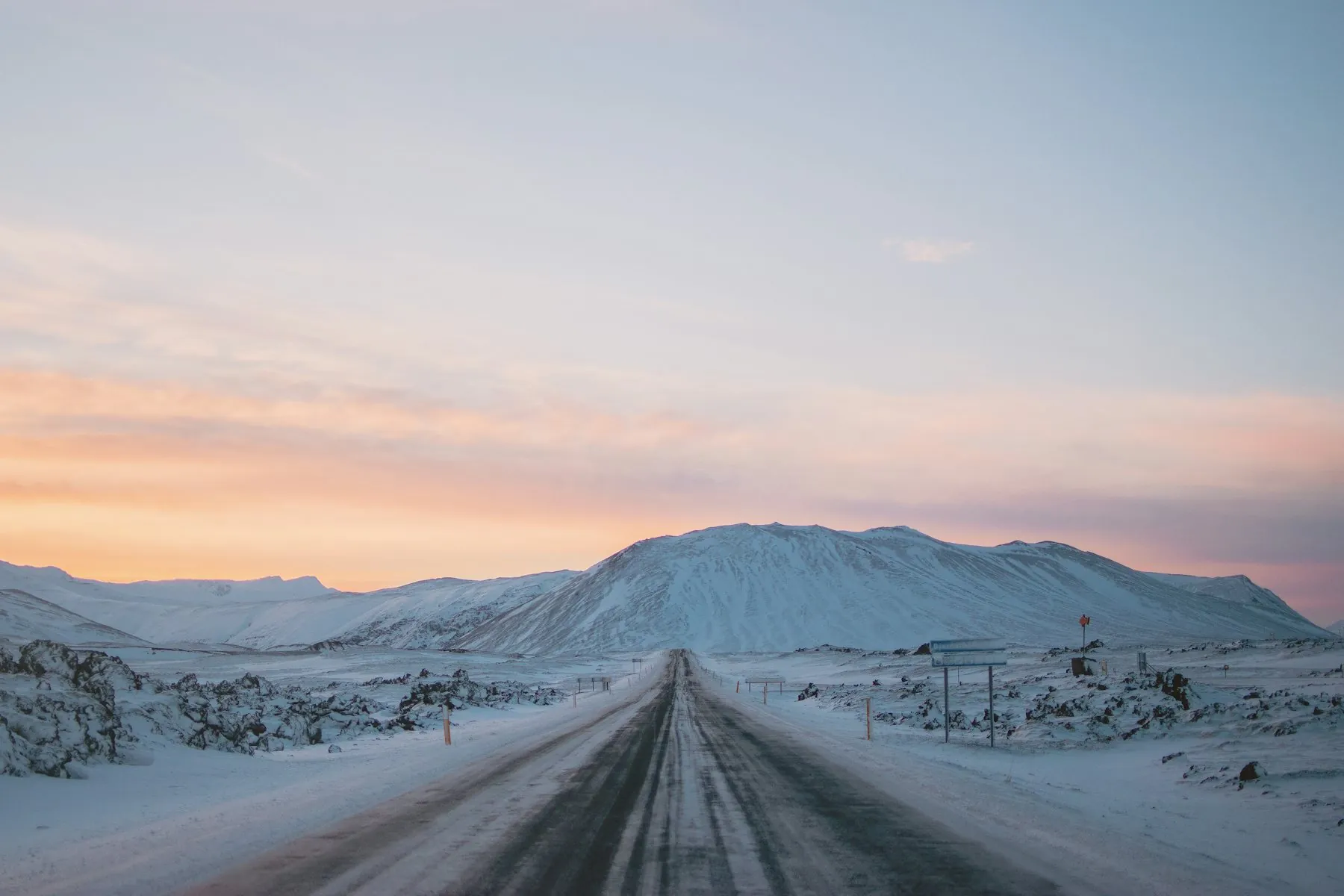 A snow-covered road leading towards mountains in north Iceland