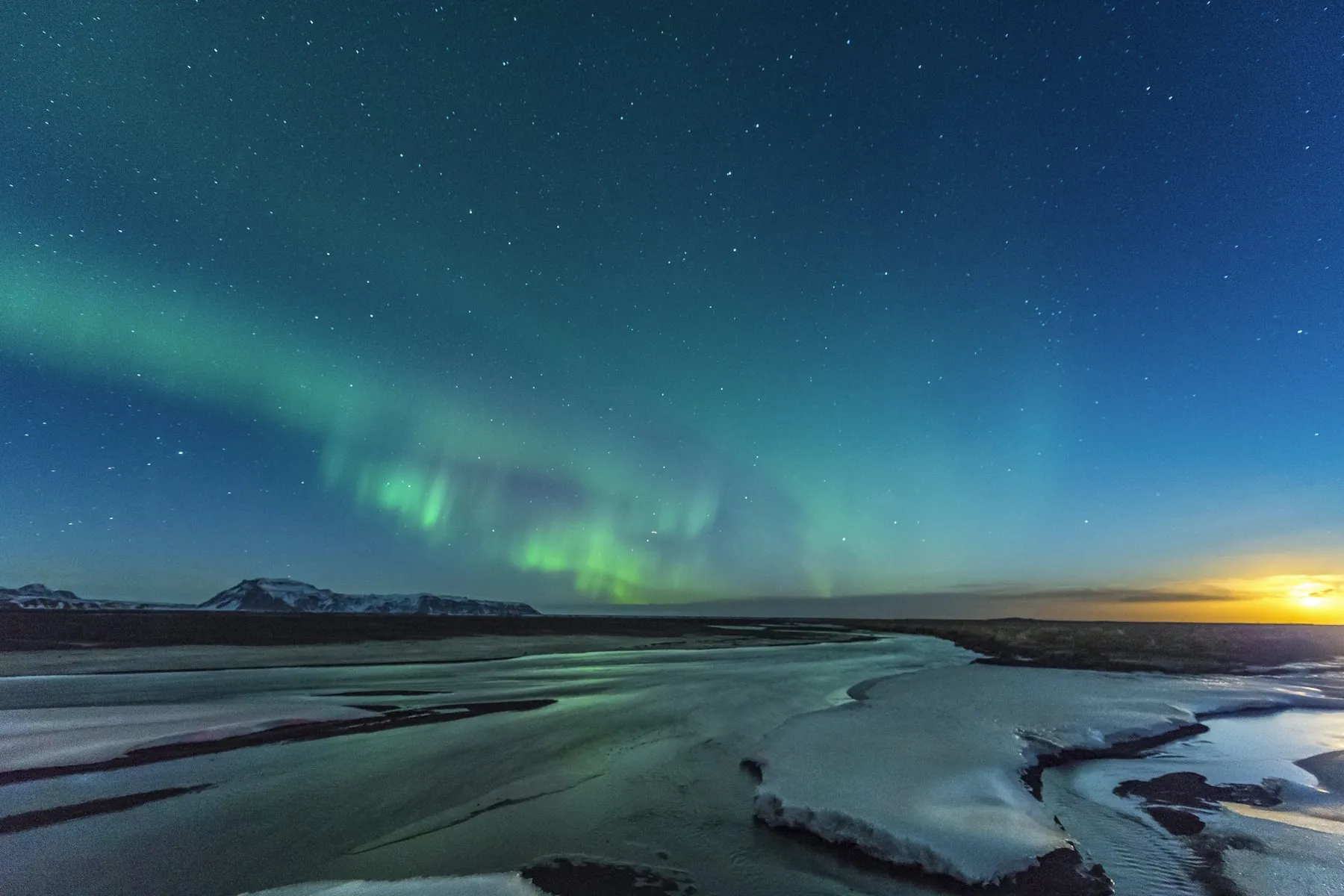 Aurora and stars over a coastline at night