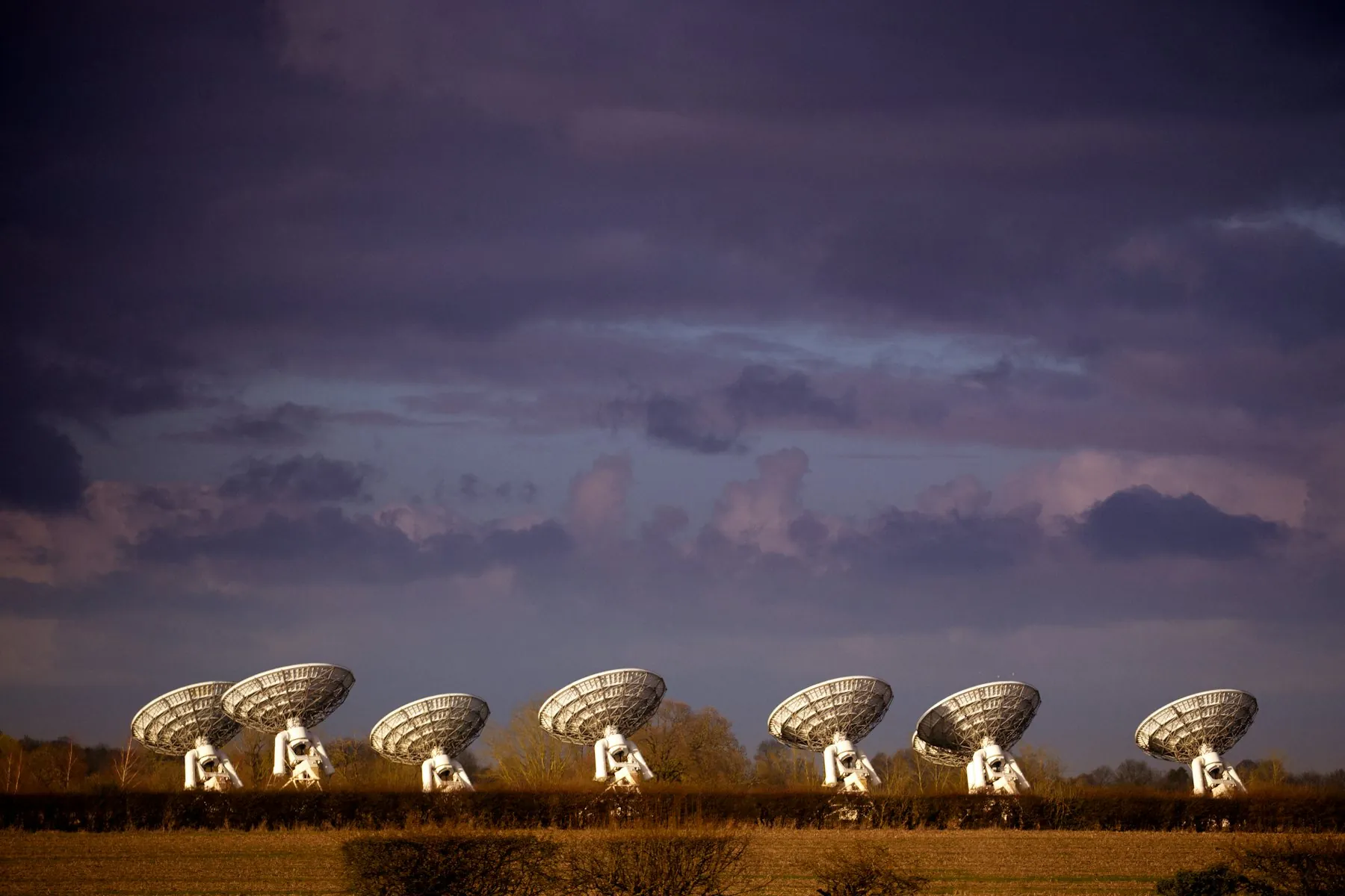 A row of satellite antennas at golden hour